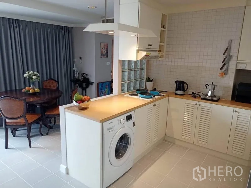 公寓 出租或出售在Watthana, Bangkok - 明亮U形厨房，木台面、灶台和前开式洗衣机。