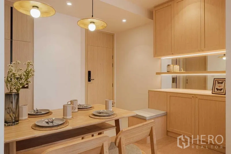 公寓 出租在Watthana, Bangkok - 木质餐桌与吊灯的用餐区，带镜面储物柜