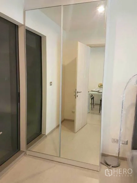 Condominium for rent in Khlong Toei, Bangkok - Bedroom with full-height mirrored wardrobe and sliding doors.