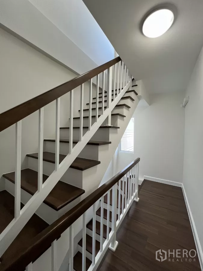 Townhouse for rent in Bang Kapi, Bangkok - Stairwell with wooden steps and white railing filled with light.