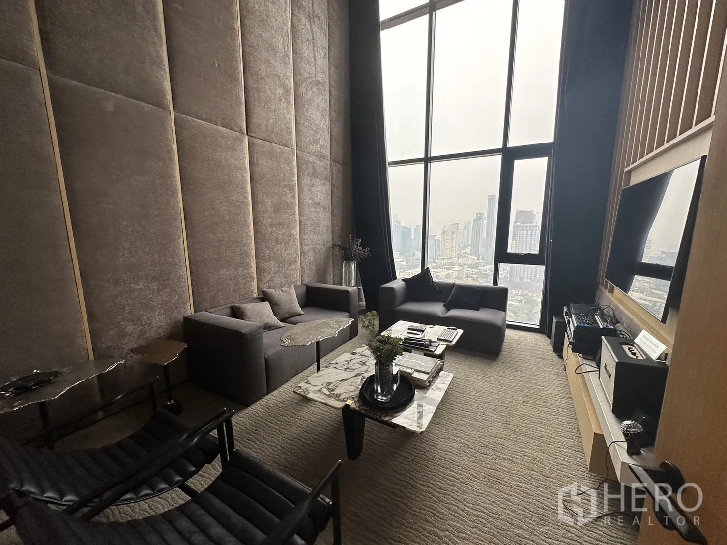 公寓 出租在Watthana, Bangkok - 双层挑高空中会客厅，沙发、电视与城市景观