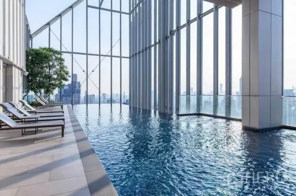 公寓 出售在Watthana, Bangkok - 天际线无边际泳池，设躺椅与高挑玻璃幕墙。