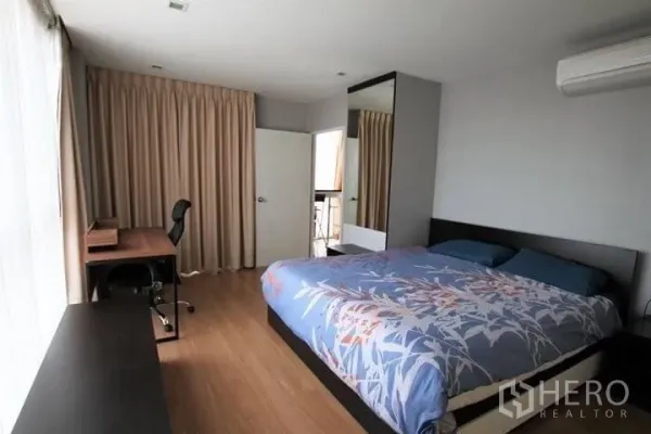 公寓 出租在Watthana, Bangkok - 主卧宽敞，配大床、书桌、落地窗帘与阳台门