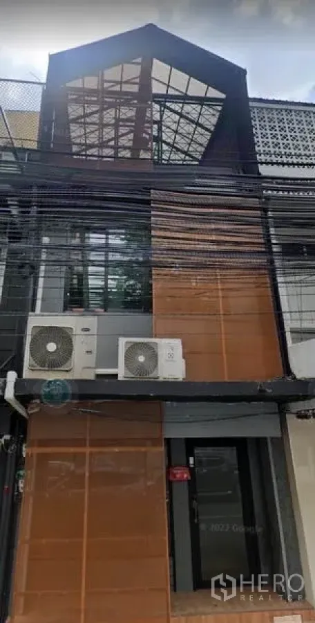带办公室的家 出售在Bang Rak, Bangkok - 现代联排家用办公楼外立面，玻璃人字顶与室外空调机组。