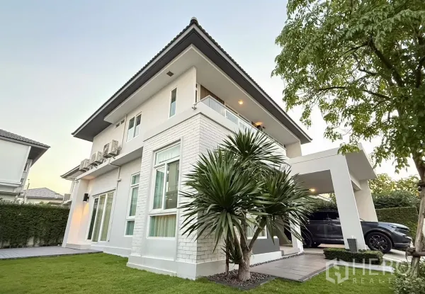 独立式住宅 出租在Prawet, Bangkok - 白色两层住宅角度视图，带阳台、车棚与草坪