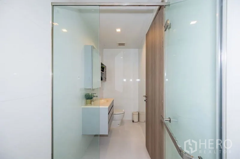 คอนโด ให้เช่าในWatthana, Bangkok - มุมมองจากตู้ shower ไปยังอ่างล้างหน้าและโถสุขภัณฑ์ในห้องน้ำโทนขาว