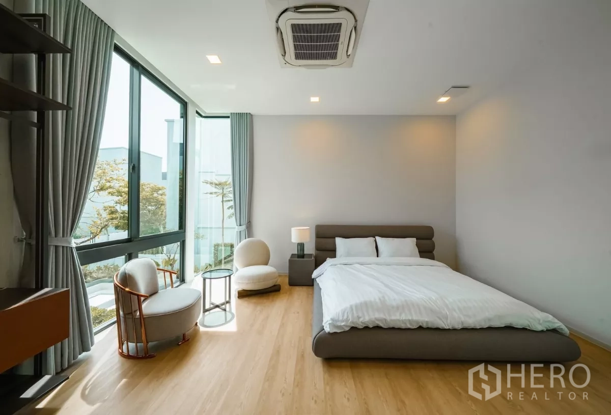 Detached House for rent or sale in Saphan Sung, Bangkok - Bright guest bedroom with corner windows and seating by the view.