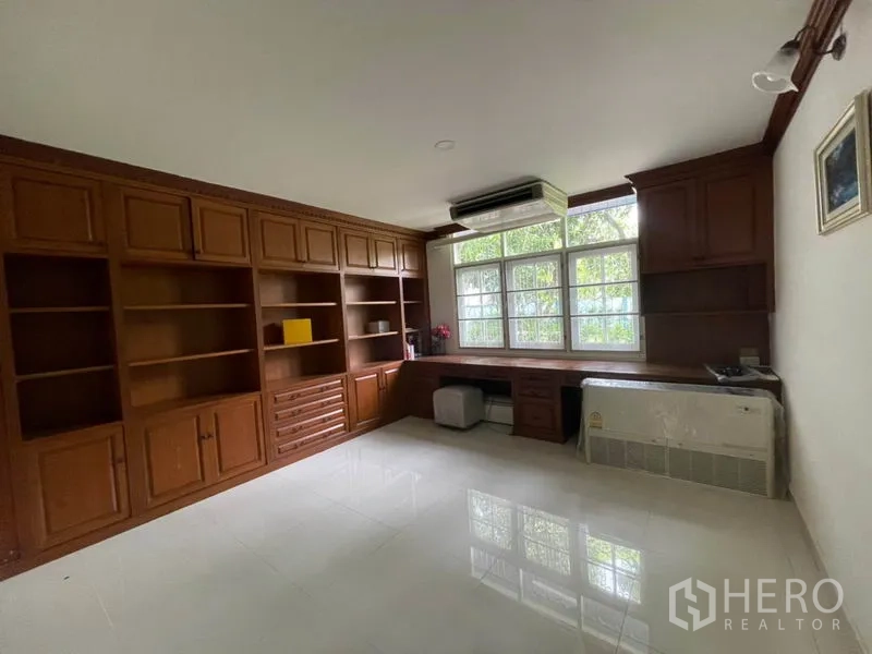 Detached House for rent in Khlong Toei, Bangkok - Wood-paneled study featuring wall-to-wall built-in bookshelves and a large window.