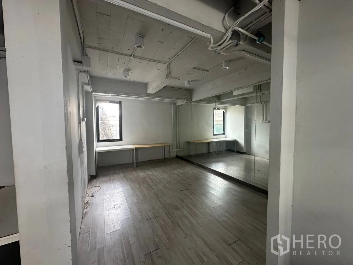Home Office for rent in Chatuchak, Bangkok - Studio-like room with laminate floor, mirrored wall and exposed ceiling pipes.
