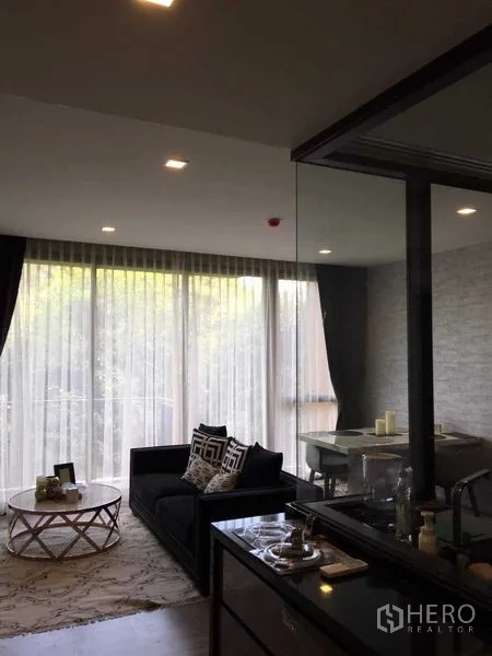 公寓 出租在Watthana, Bangkok - 开放式客厅与餐区，落地纱帘通往阳台。