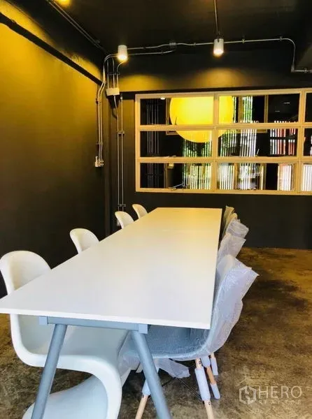 Home Office for rent in Huai Khwang, Bangkok - Meeting room with a long white table, white chairs and minimalist lighting.