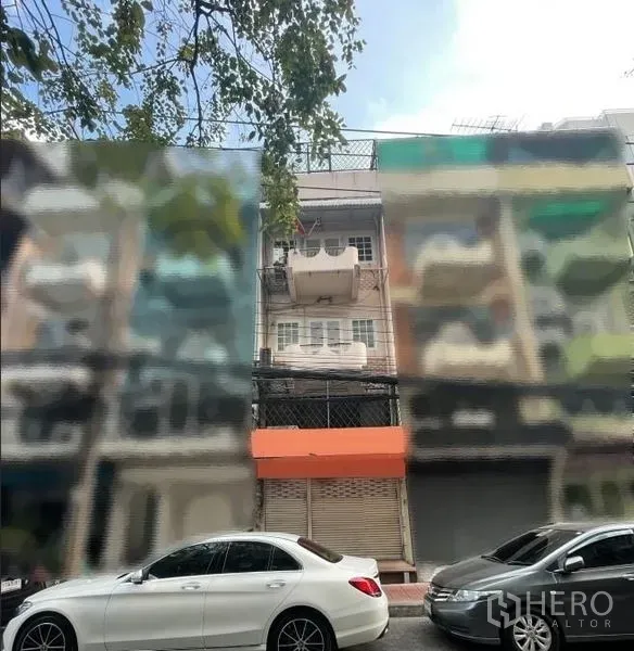 店屋 出租在Phaya Thai, Bangkok - 街景视角，一排店屋与路边车辆，突出橙色雨棚的单位。