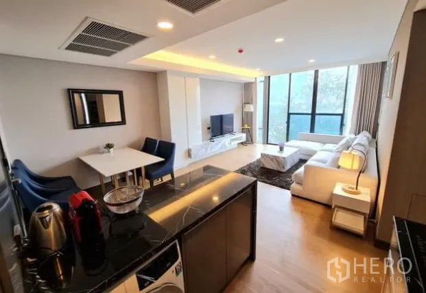 Condominium for rent in Khlong Toei, Bangkok - Open‑plan kitchen and living space with black stone island and two‑seat dining table.