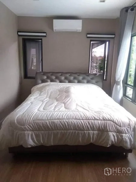 Detached House for rent or sale in Saphan Sung, Bangkok - Master bedroom with large bed, corner windows and air conditioner.