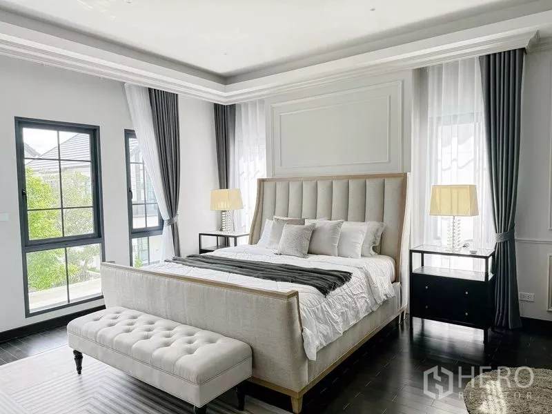 Detached House for rent or sale in Bang Phli, Samut Prakan - Bright master bedroom with large upholstered bed, bench and multiple tall windows.