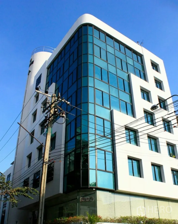 Office Space for rent in Suan Luang, Bangkok - Modern mid-rise office building with blue-tinted glass facade and white exterior under a clear sky.