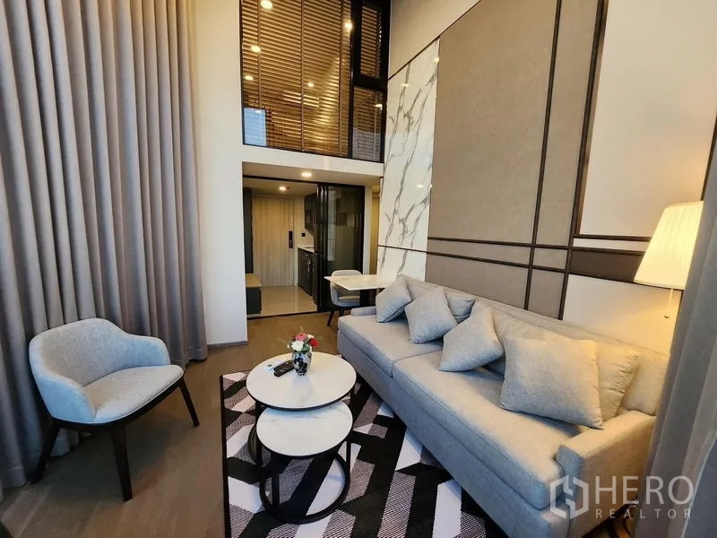 Condominium for rent - Loft-style living area with mezzanine above and a compact kitchen behind sliding glass doors.