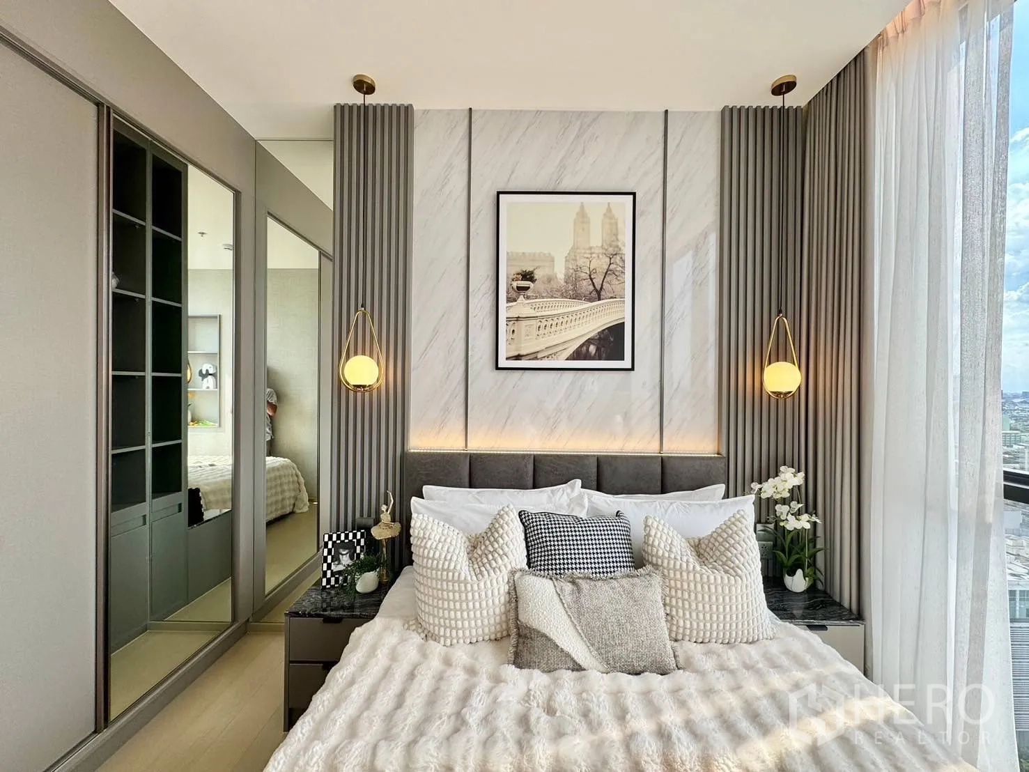 Condominium for rent in Ratchathewi, Bangkok - Bedroom headboard wall with pendant lights, mirrored wardrobe, and sheer curtains.