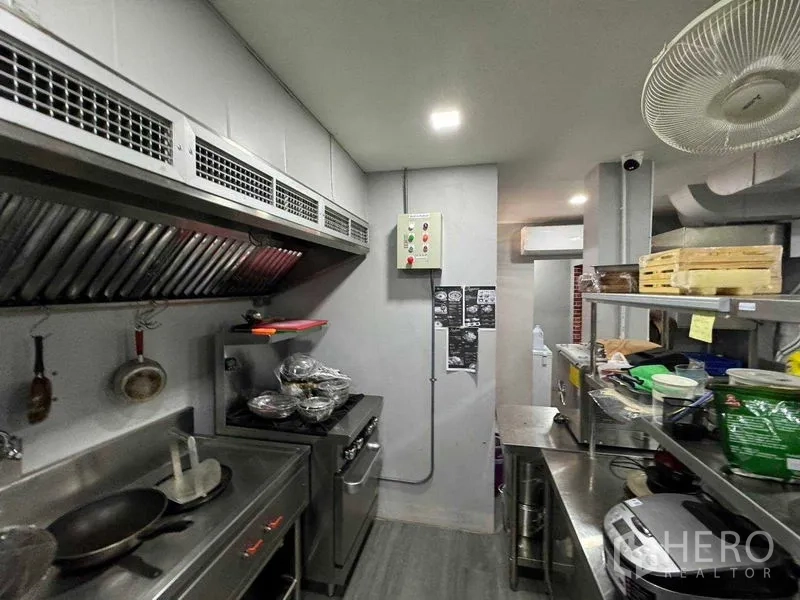 Shophouse for rent in Watthana, Bangkok - Commercial kitchen with ventilation hood, stainless prep counters and a gas range.