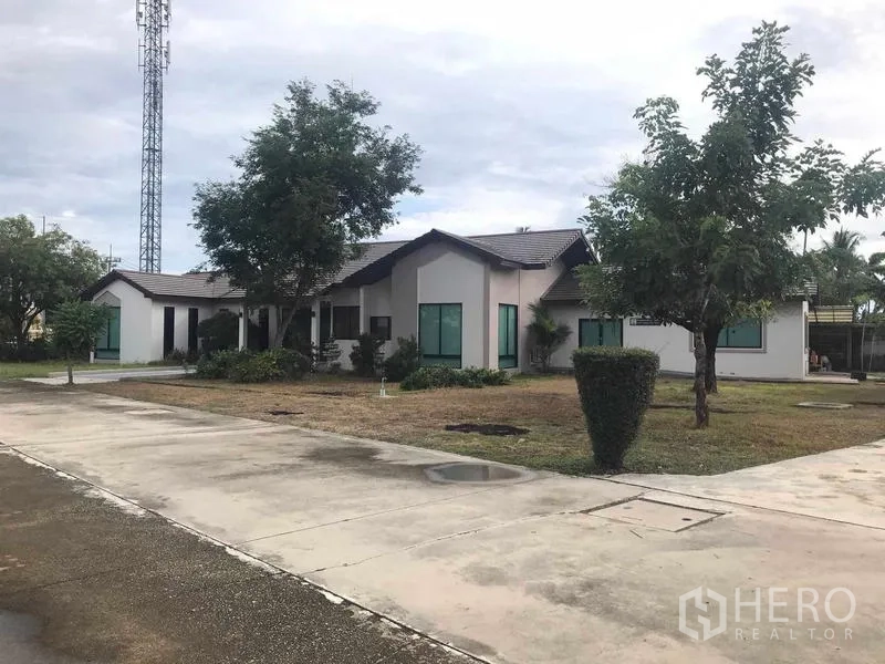 Warehouse for sale in Chon Buri - Low-rise residential or office pavilion set beside a paved driveway and landscaped grounds.