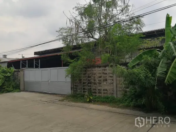 货栈 出租在Min Buri, Bangkok - 仓库外观街景，高围墙与金属滑门的独立院落