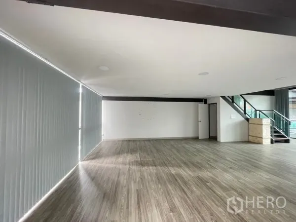 办公空间 出租在Bang Na, Bangkok - 大面积办公区，通往夹层的楼梯、白色墙面与独立房门。