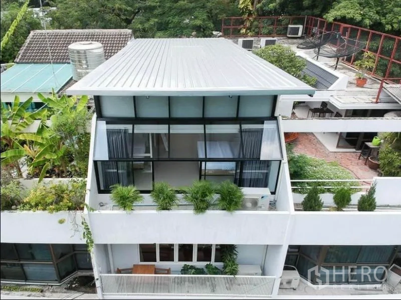 联排别墅 出租在Khlong Toei, Bangkok - 现代多层联排别墅外立面，大片落地窗、屋顶与绿植点缀