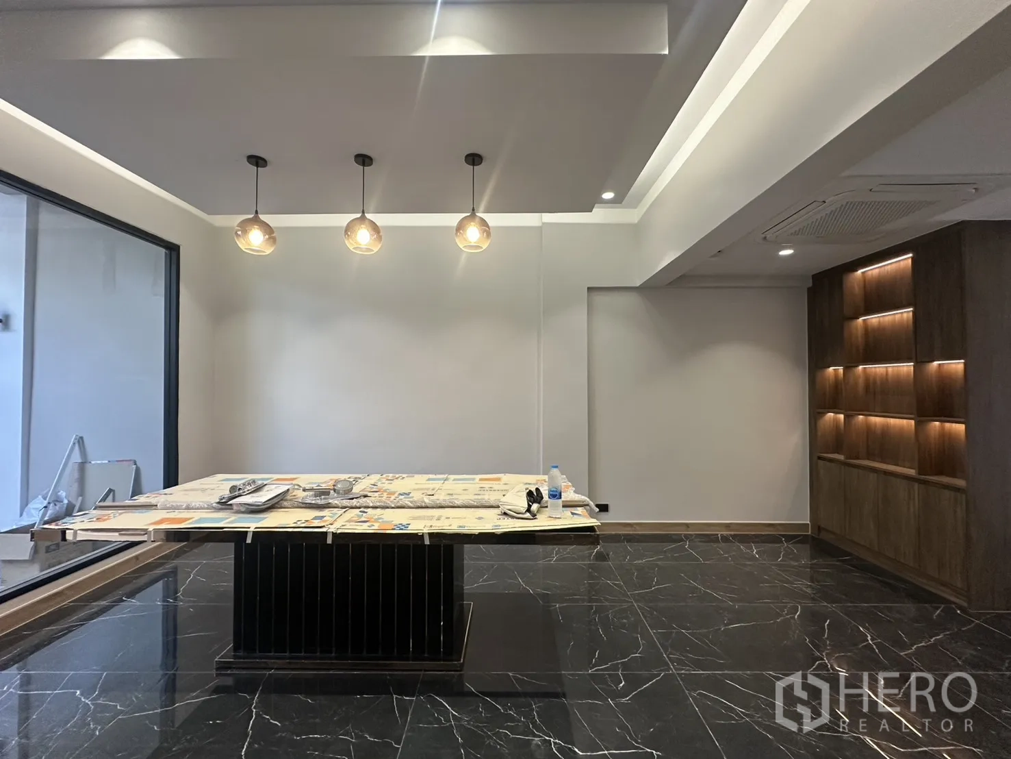 家庭办公室 for rent in Watthana, Bangkok - 吊灯点缀的房间，中央摆放桌子并有展示柜。