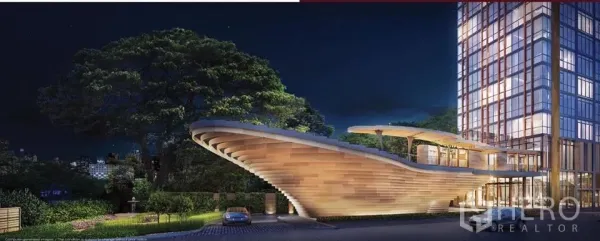 Condominium for sale in Watthana, Bangkok - Night exterior of a high-rise with a dramatic curved podium and landscaped arrival driveway.