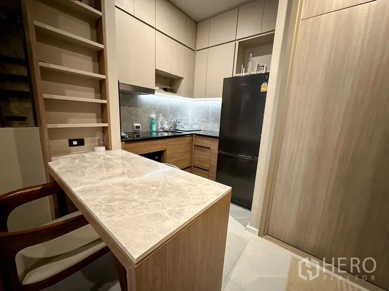 公寓 出租在Pathum Wan, Bangkok - 厨房视角，带大理石台面吧台和全尺寸冰箱。
