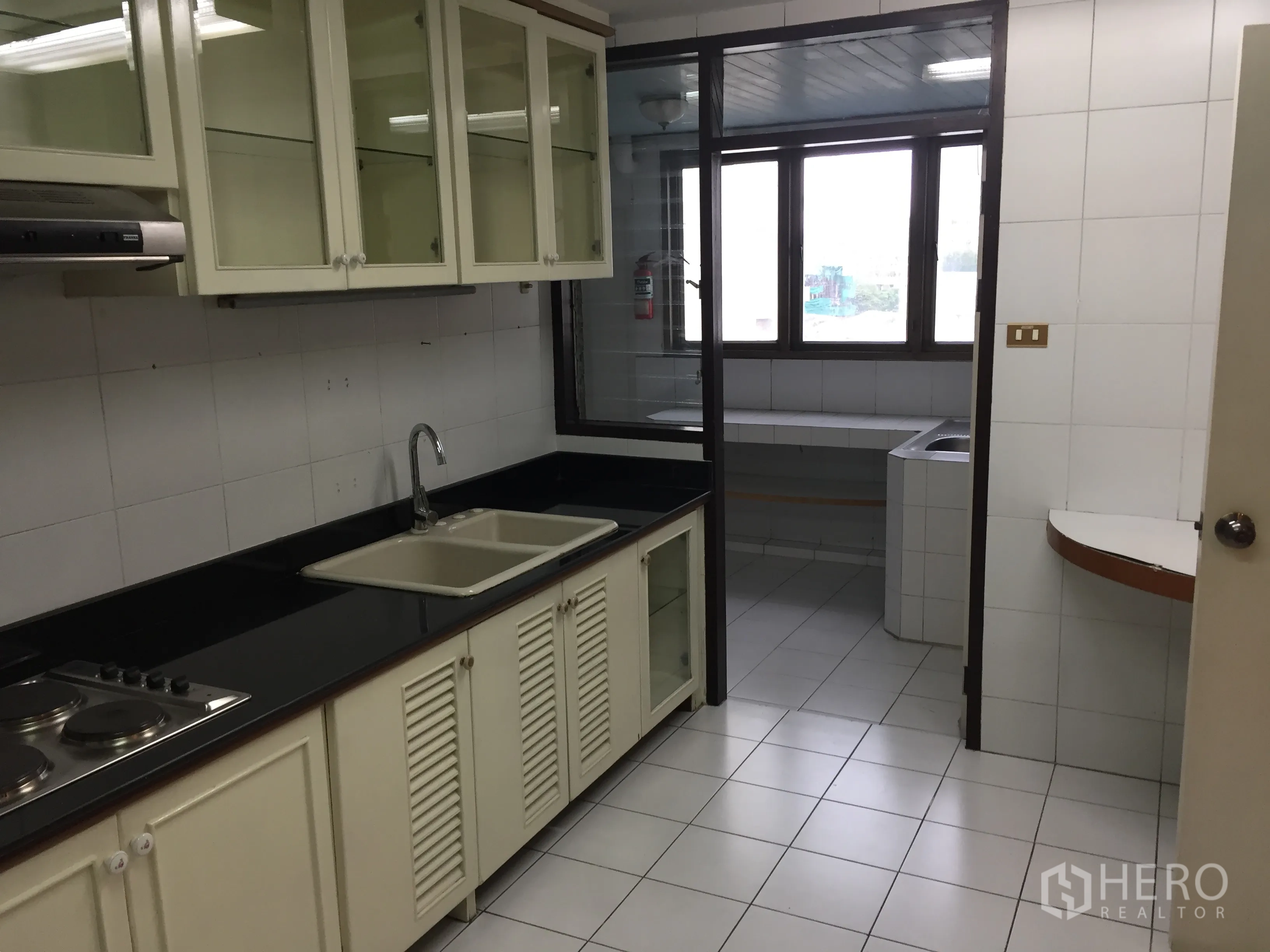 公寓 出租在Watthana, Bangkok - 封闭式厨房，黑色台面、玻璃吊柜、电炉和双槽水槽