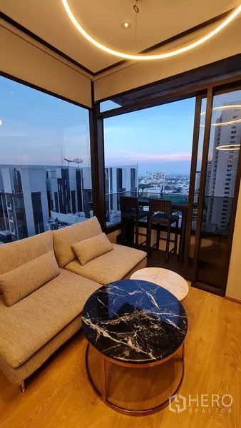 公寓 出租在Watthana, Bangkok - 客厅配沙发与圆形大理石茶几，连接观景阳台。