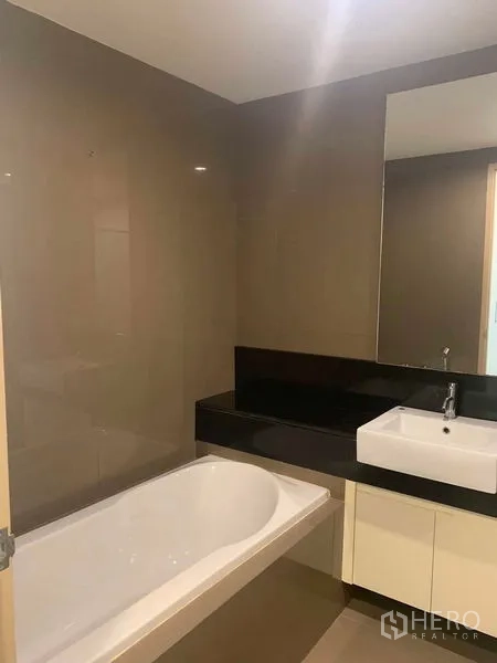 Condominium for rent or sale in Khlong Toei, Bangkok - Modern bathroom with bathtub, vanity, and large mirror.