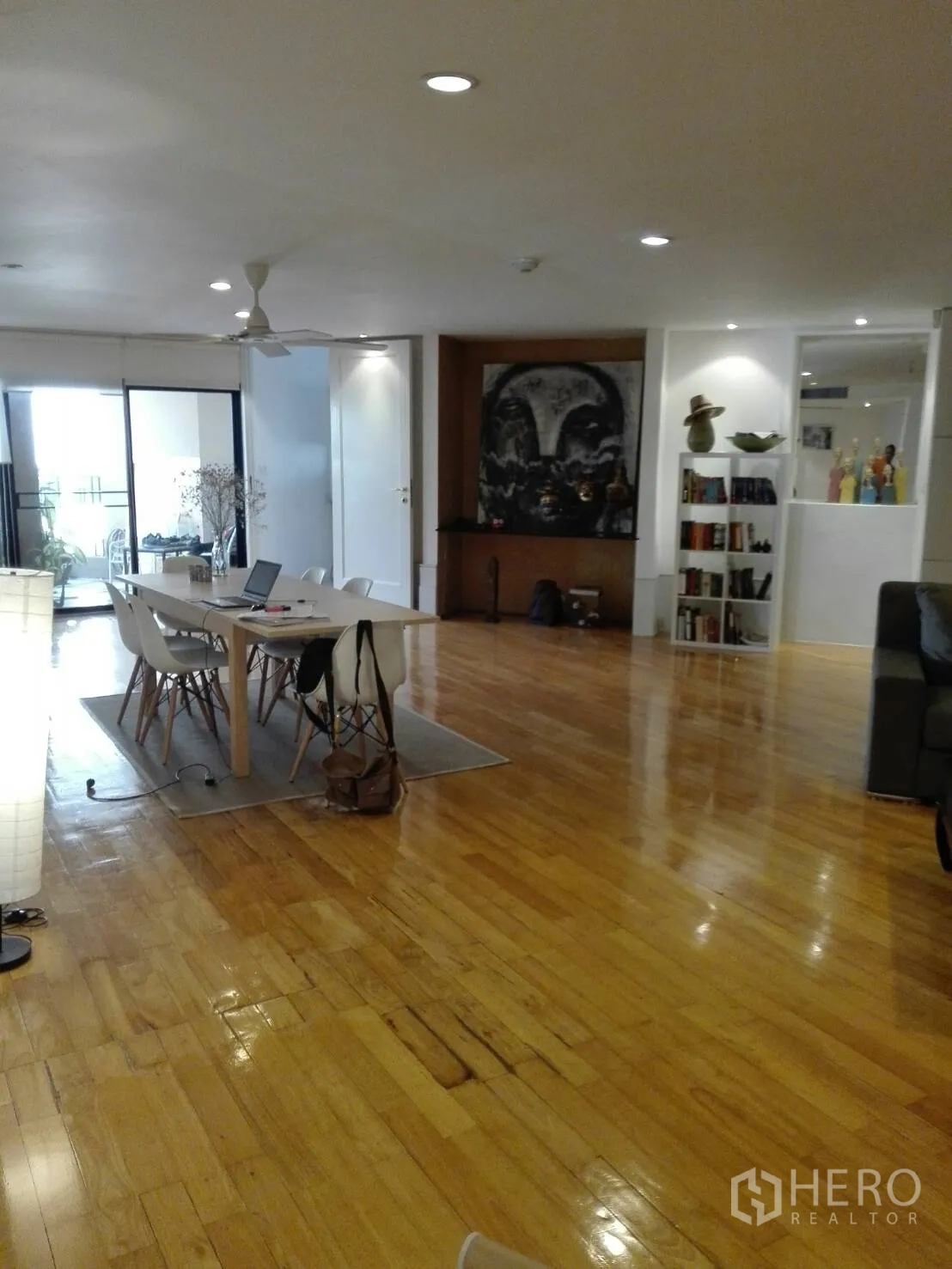 Condominium for rent in Khlong Toei, Bangkok - Open-plan living and dining area with polished hardwood floors, ceiling lights and built-in shelving.