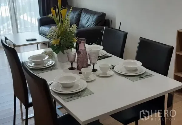 Condominium for rent in Khlong Toei, Bangkok - Modern dining area with set tableware for four adjacent to the living room in a Bangkok condominium.