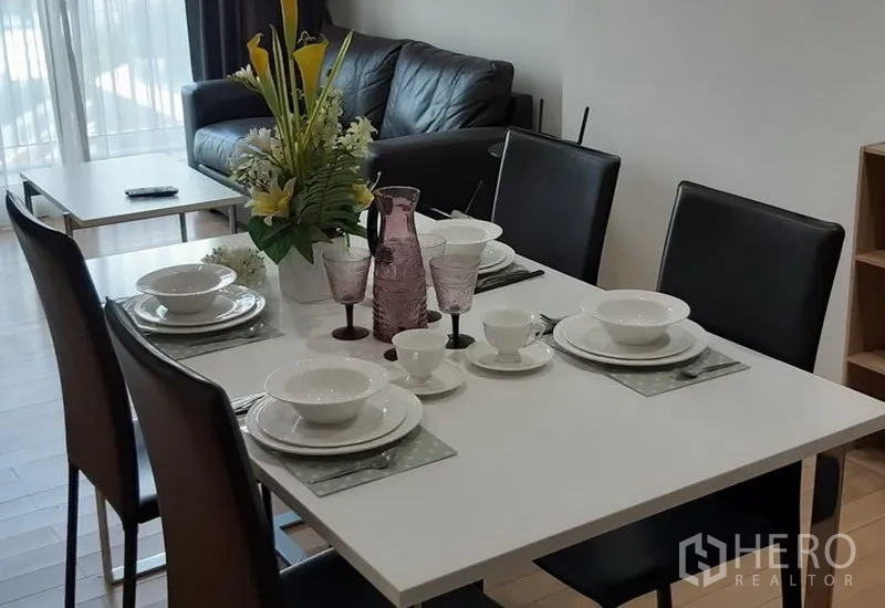 Condominium for rent in Khlong Toei, Bangkok - Modern dining area with set tableware for four adjacent to the living room in a Bangkok condominium.