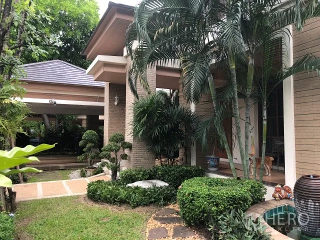 Detached House for rent in Bang Phli, Samut Prakan - Tropical landscaped front yard with palm trees, brick facade and a covered carport of a detached house in Bang Phli.
