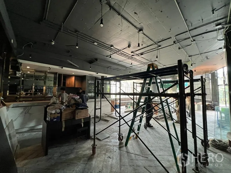 Retail Space for rent - Spacious interior under renovation with exposed ceiling, a long bar counter and scaffolding.