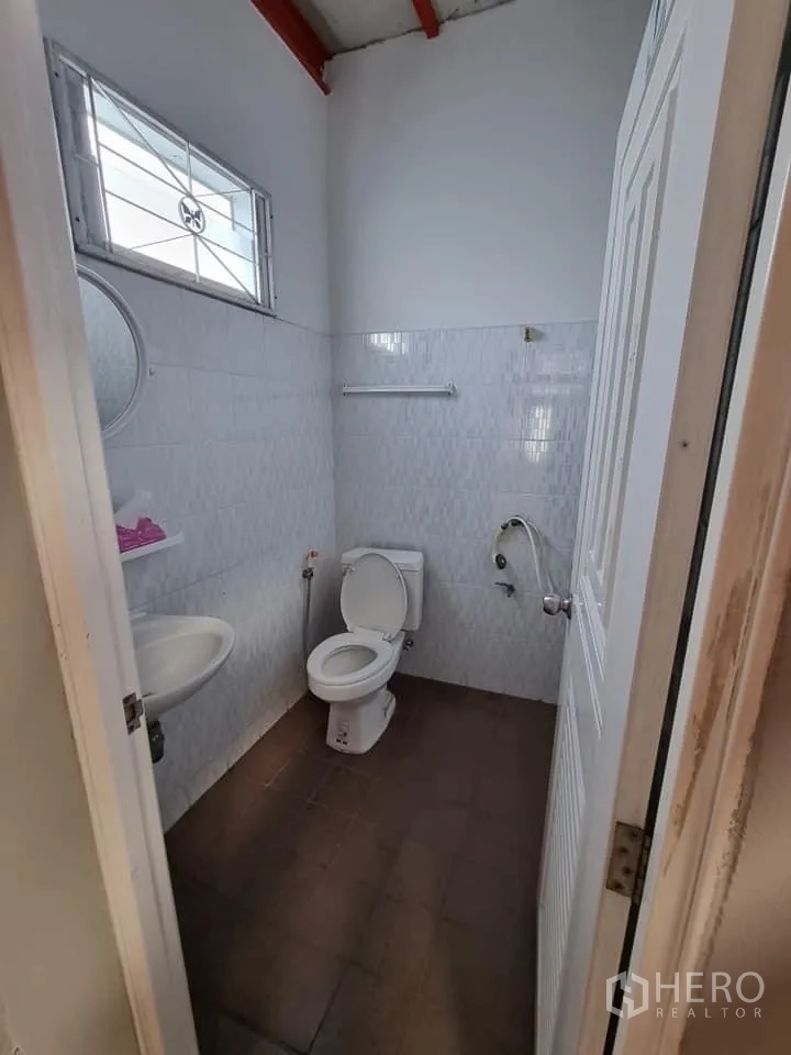 Warehouse for rent in Lam Luk Ka, Pathum Thani - Clean restroom with toilet, sink and a small window inside the warehouse.