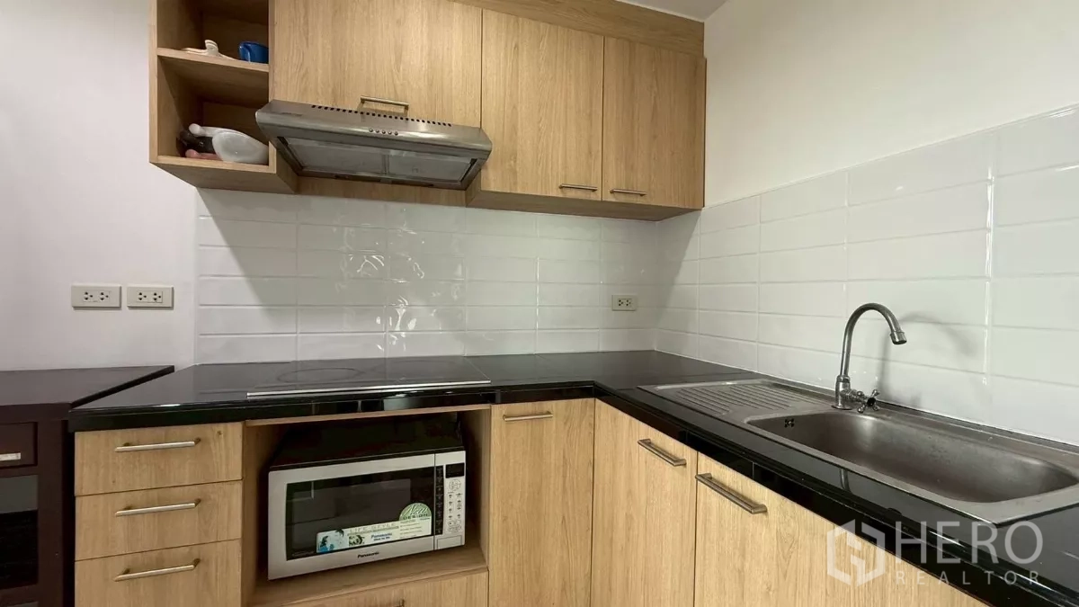 公寓 出售在Yan Nawa, Bangkok - 独立厨房，木质柜体、黑色台面与白色瓷砖墙面。