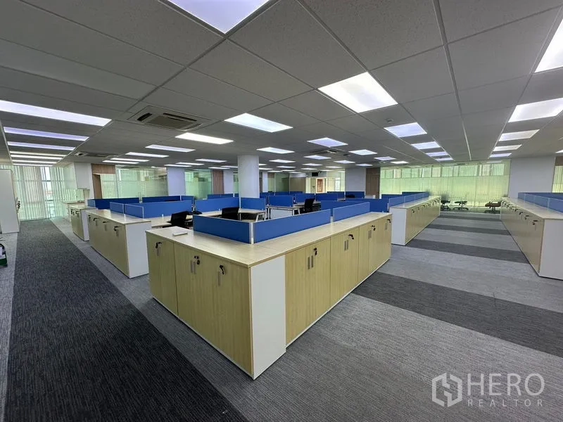 办公空间 出租 - 开放式办公区，蓝色隔断工位、储物柜、地毯地面与LED吊顶灯。