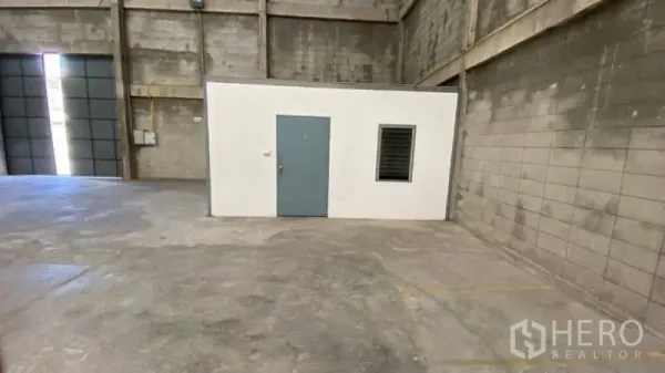 Warehouse for rent in Prawet, Bangkok - Small internal office room with door and window inside a high-bay warehouse near the loading entrance.
