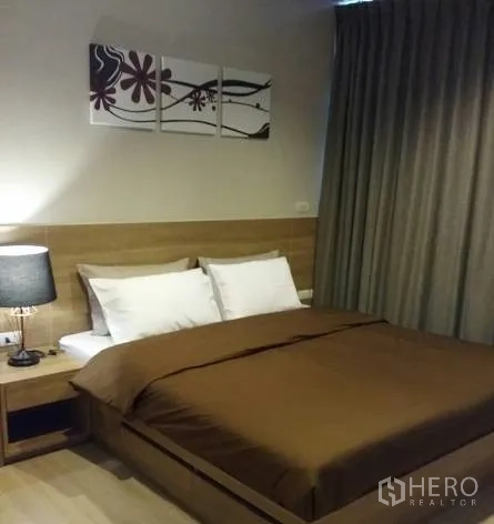 公寓 出租在Sathon, Bangkok - 主卧木质床头，棕色床品，床头灯与遮光窗帘。