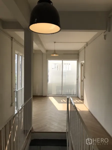 独立式住宅 出租或出售在Din Daeng, Bangkok - 明亮的二楼走廊，吊灯、鱼骨纹木地板与推拉玻璃门。