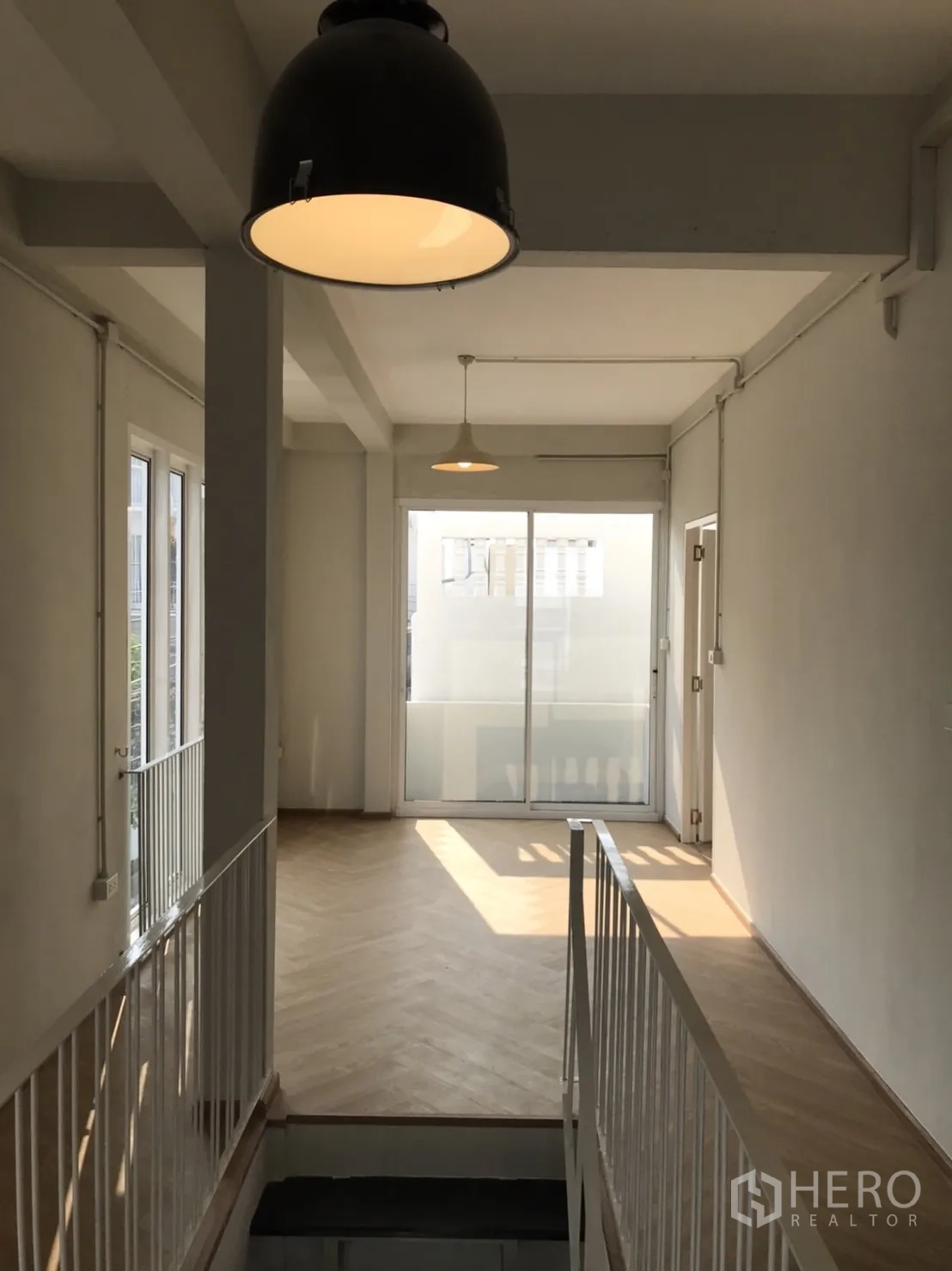 独立式住宅 出租或出售在Din Daeng, Bangkok - 明亮的二楼走廊，吊灯、鱼骨纹木地板与推拉玻璃门。