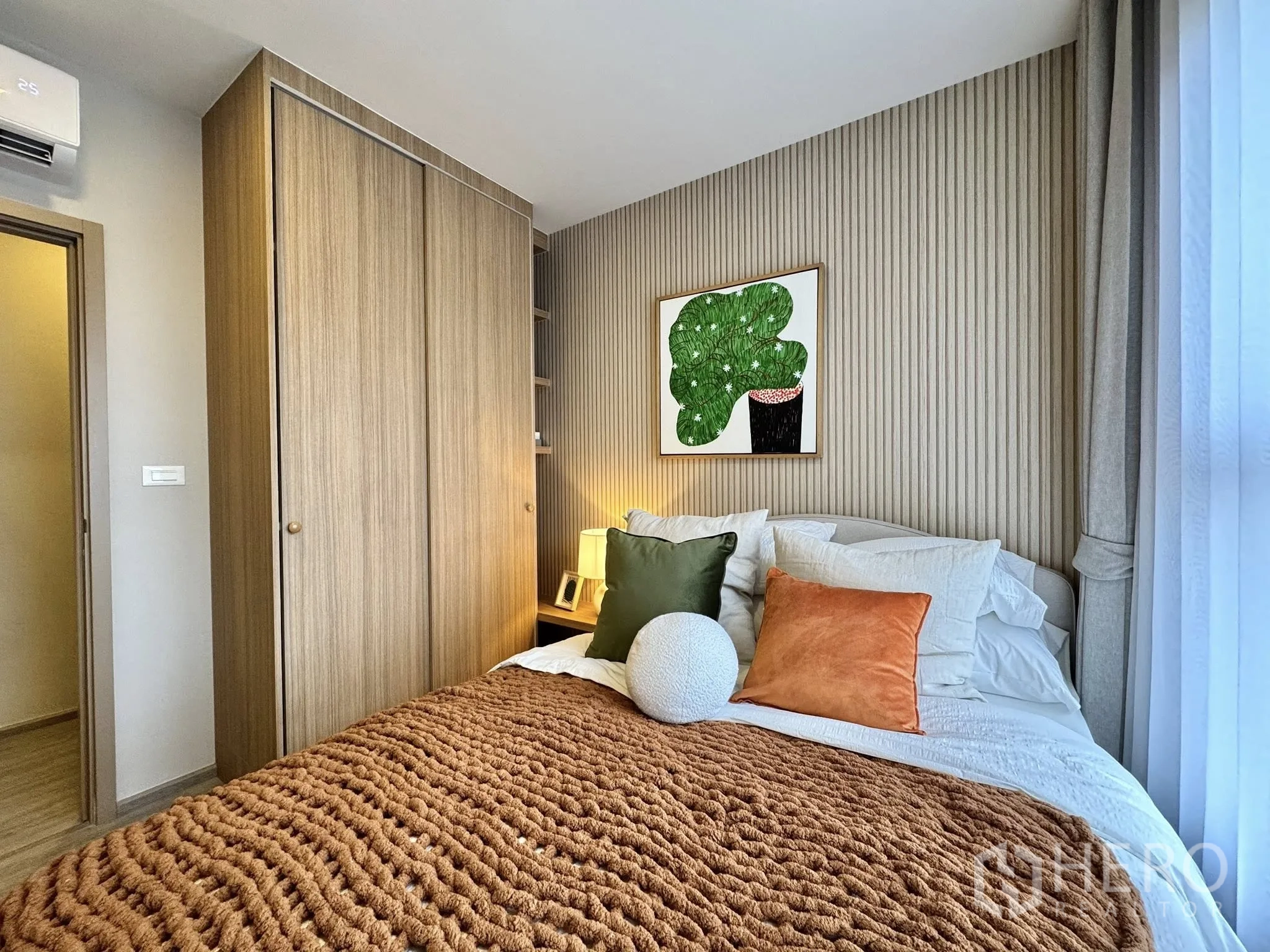 Condominium for rent in Watthana, Bangkok - Bedroom with textured blanket, large wardrobe, air conditioner, and window drapes.
