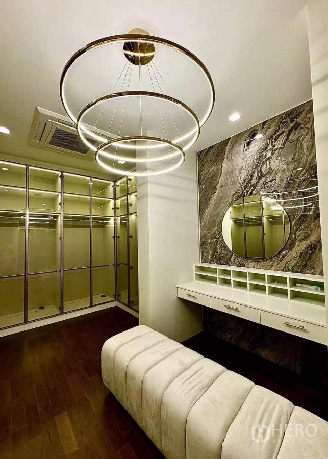 Detached House for sale in Saphan Sung, Bangkok - Large walk-in closet with upholstered bench, makeup vanity and circular chandelier.