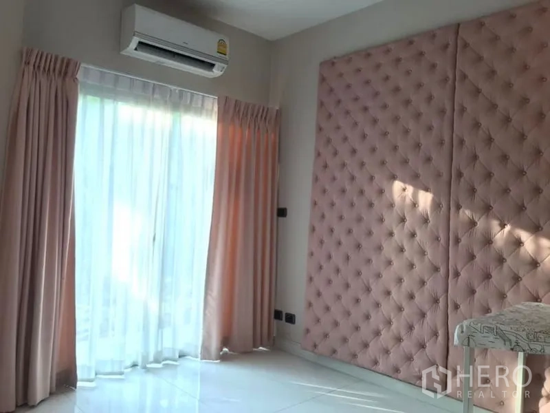 Detached House for sale in Saphan Sung, Bangkok - Sunlit room with pink tufted wall panel, sliding glass door and sheer curtains.