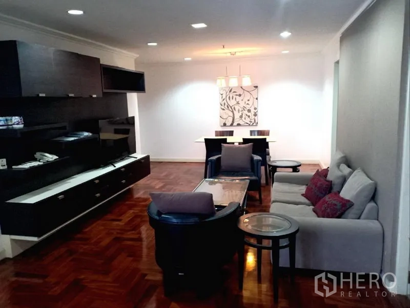 公寓 出租在Watthana, Bangkok - 宽敞客餐厅，木地板、内置电视墙与沙发，吊灯照明的曼谷公寓。