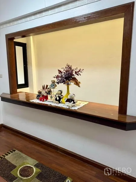 Home Office for rent in Khlong Toei, Bangkok - Recessed display nook with wooden shelf and patterned rug in living space.